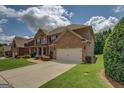 Elegant brick home exterior with a spacious driveway, lush lawn, and well-manicured landscaping at 312 Relative Trl, Mcdonough, GA 30253