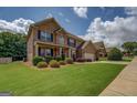 Beautiful brick home exterior featuring a well-maintained lawn, shrubs, and ample driveway space at 312 Relative Trl, Mcdonough, GA 30253