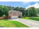 A spacious home with a long driveway and lush green lawn surrounded by mature trees at 1605 Cascade Overlook, Peachtree City, GA 30269