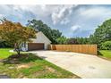 Spacious driveway leading to a garage, complemented by a wooden fence and landscaping at 858 Pates Creek Rd, Stockbridge, GA 30281