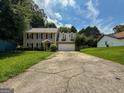 Charming two-story home with a lush green lawn and a cracked driveway leading to the garage at 5156 Allison Way, Sugar Hill, GA 30518