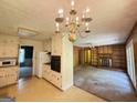 Kitchen with white cabinetry, appliances, chandelier, open to fireplace living room at 402 Stone St, Oxford, GA 30054