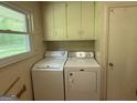 Functional laundry room featuring a washer, dryer, and storage cabinets at 402 Stone St, Oxford, GA 30054