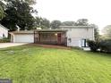 Inviting home featuring a covered porch, attached garage, and well-maintained lawn and mature landscaping at 5670 Bob White Ln, Douglasville, GA 30135