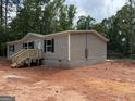 Exterior side view of a newly built home, showing the siding and block foundation in a wooded area at 436 Laurel Trce, Carrollton, GA 30116