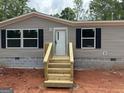 A close up of the front entrance showing the new wooden steps, gray siding, black shutters, and block foundation at 436 Laurel Trce, Carrollton, GA 30116