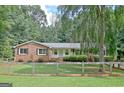 Inviting brick home with a fenced yard and a lush lawn, surrounded by mature trees at 110 Heatherwood Dr, Fayetteville, GA 30215