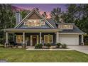 Charming home at dusk featuring a welcoming front porch with rocking chairs and well-manicured landscaping at 9148 Tarnwood Dr, Villa Rica, GA 30180