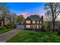 Dusk shot of a beautiful two-story home featuring a brick facade, attached garage, and illuminated interior at 3797 Churchill Sw Dr, Marietta, GA 30064