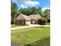 Traditional brick home with well-maintained lawn, mature landscaping, and a long driveway to attached garages at 223 Overland Trl, Mcdonough, GA 30252