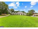 Well-manicured front lawn and lush trees surround this traditional ranch-style home at 115 Fernway Dr, Fayetteville, GA 30214