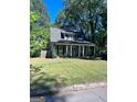 Charming home with well-kept lawn, inviting front porch with pillars and a lush, green tree canopy at 1225 Bridges Ave Sw, Atlanta, GA 30310