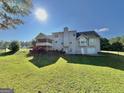 Spacious backyard featuring a large lawn, deck, screened-in porch, with mature trees on a sunny day at 116 Cardell Farms Rd, Locust Grove, GA 30248
