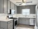 Updated kitchen boasts stainless steel appliances, gray cabinetry, white countertops, and new flooring at 116 Cardell Farms Rd, Locust Grove, GA 30248