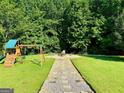 A backyard featuring a playset, a swing set, and a fire pit surrounded by lush greenery at 5388 Silver Springs Dr, Sugar Hill, GA 30518