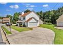 View of the home showcasing a long driveway leading to a garage and complemented by a lush, green lawn at 7770 Hana Court Ct, Jonesboro, GA 30236