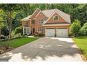 Elegant brick home featuring a two-car garage, lush landscaping, and a spacious driveway in a tranquil setting at 3245 Bywater Trl, Roswell, GA 30075