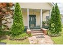 Inviting front porch with green door, framed by manicured evergreen trees and lush ground cover, creates a welcoming entrance at 178 S Old Highway 27, Roopville, GA 30170