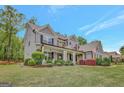 Beautiful home featuring lush lawn, stone accents, and a charming front porch with rocking chairs at 185 Discovery Lake Dr, Fayetteville, GA 30215