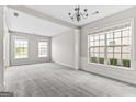 Bright living room featuring neutral carpet, large windows, and elegant chandelier providing ample natural light at 8750 Redford Ln, Suwanee, GA 30024