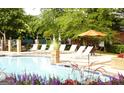 Inviting community pool with ample lounge seating, a shade umbrella, and colorful surrounding foliage at 433 Abbey Springs Way, Mcdonough, GA 30253