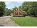 Brick home with attached garage, manicured lawn and surrounded by mature trees at 140 Alford Dr, Fayetteville, GA 30215