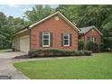 Charming brick home with attached garage, manicured lawn and mature trees at 140 Alford Dr, Fayetteville, GA 30215