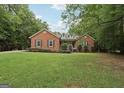 Inviting brick home with dormer windows and lush lawn surrounded by mature trees at 140 Alford Dr, Fayetteville, GA 30215