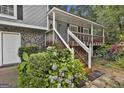 Inviting covered front porch with wooden steps, railing, and surrounding lush landscaping at 9138 Sunset Dr, Jonesboro, GA 30238