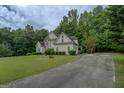 View of the home with a circular driveway, lush lawn, and wooded surroundings at 235 Rustic Mill Ln, Fayetteville, GA 30214