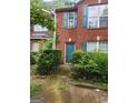Traditional red brick townhouse featuring a teal front door, shutters, and well kept shrubbery at 2756 Norfair Loop, Lithonia, GA 30038