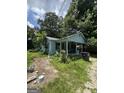 Charming single-story home featuring a quaint front porch, light blue siding, and an unkempt front yard at 8373 Chicago Ave, Douglasville, GA 30134