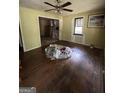 Empty living room with original hardwood floors, ceiling fan, and natural light, needs some renovation at 8373 Chicago Ave, Douglasville, GA 30134