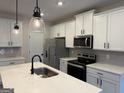 Modern kitchen boasts stainless steel appliances, stylish pendant lighting, and quartz countertops at 422 Cantrell Drive, Dallas, GA 30157