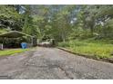Long, paved driveway leading to the property with a covered parking area on the left at 6220 Petersburg Rd, Fairburn, GA 30213