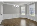 Elegant dining room featuring hardwood floors, decorative molding, a chandelier, and bright natural light from large windows at 2004 Brittlebank Ln, Lawrenceville, GA 30043