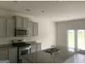 Modern kitchen with stainless steel appliances, granite countertops, a kitchen island with sink, and gray cabinets at 1636 Jersey Dr, Stockbridge, GA 30281