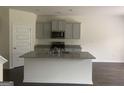 Open-concept kitchen with a center island, granite countertops, gray cabinets, and stainless steel appliances at 1636 Jersey Dr, Stockbridge, GA 30281
