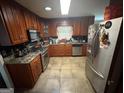 Functional kitchen with wood cabinets, tile floors, and modern stainless steel appliances at 2119 Amherst Se Trl, Conyers, GA 30094