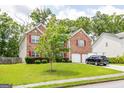 View of the property with lush green lawn, mature trees, and a brick facade in a beautiful neighborhood at 1849 Wanda Way, Ellenwood, GA 30294