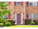 Close-up of the brick home's entry featuring a dark-colored front door, sidelights, and neat landscaping at 1849 Wanda Way, Ellenwood, GA 30294
