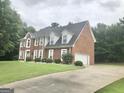 Traditional two-story brick home featuring an attached garage and a well-manicured lawn at 1433 Cotton Sw Trl, Conyers, GA 30094