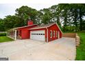 Exterior shot showcasing the red house, the expansive concrete driveway, and the multi-car garage at 125 Point View Ct, Tyrone, GA 30290