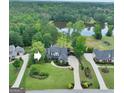 Aerial view of a beautiful home with lush landscaping, a serene pond, and mature trees at 383 Beaumont Farms Dr, Sharpsburg, GA 30277