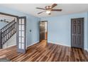 Bedroom with light blue walls, a ceiling fan, wood-look flooring, and a view of the staircase at 424 Browning Field Way, Hampton, GA 30228