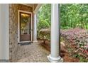 Charming covered front porch with brick flooring, white columns, and colorful foliage, offering a warm welcome at 50 Star Spangled Ln, Peachtree City, GA 30269