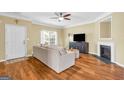 Bright living room featuring hardwood floors, a ceiling fan, modern furniture, and a cozy fireplace at 401 Buckboard Ln, Locust Grove, GA 30248