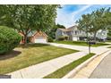 View of the brick home with a lush green lawn, long driveway, and neighboring homes in a residential area at 2504 Plymouth Way, Conyers, GA 30013
