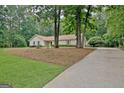 View of ranch home from a driveway with a backdrop of mature trees and natural surroundings at 210 Grandchester Way, Fayetteville, GA 30215