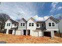 New townhomes with neutral siding, garages and covered entries beneath black rooflines at 11594 E Lovejoy Rd # 1, Hampton, GA 30228